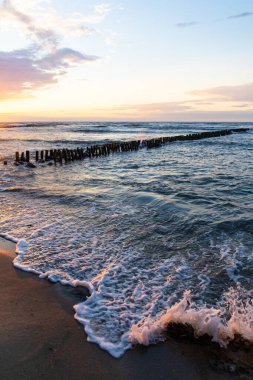 Yaz günbatımının parlak yumuşak renkleri dalgalı deniz ve sahil kenarında.