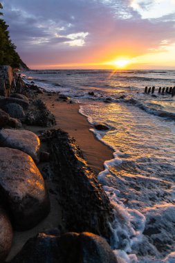 Yaz günbatımının parlak yumuşak renkleri deniz kenarında ve kumsalda taşlarla