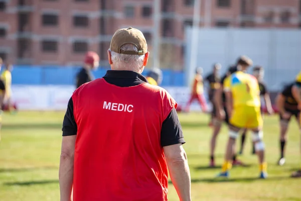 sports medic from the edge of the field watching the game