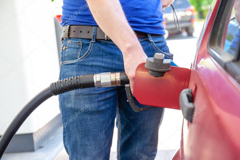 man fills petrol in the car at the gas station