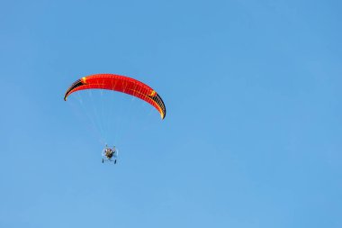 bright paraglider with a motor flies in the blue sky