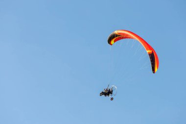 bright paraglider with a motor flies in the blue sky