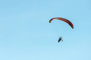 bright paraglider with a motor flies in the blue sky