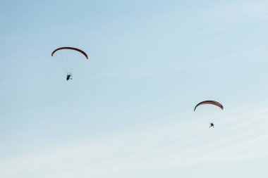 two paraglider with a motor flies in the blue sky