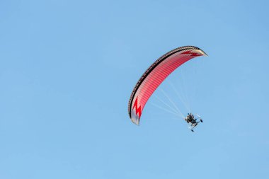 bright paraglider with a motor flies in the blue sky
