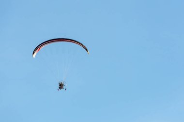 bright paraglider with a motor flies in the blue sky