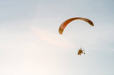 bright paraglider with a motor flies in the blue sunny sky