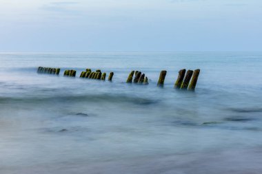 Mavi alacakaranlıkta sudan sarkan dalgalı suyla deniz yüzeyine uzun süre maruz kalacaksınız.