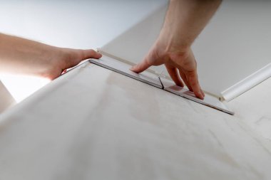 Duvara beyaz kiremit yapıştıran inşaatçının elleri