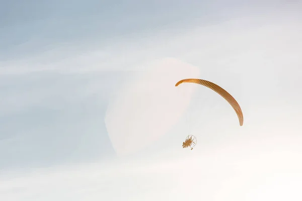 青い晴れ空を飛ぶモーター付きの明るいパラグライダー — ストック写真