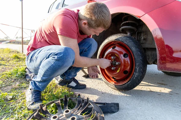 Sürücü patlak tekerleği yol boyunca geçici bir tekerle değiştiriyor, yakın plan.