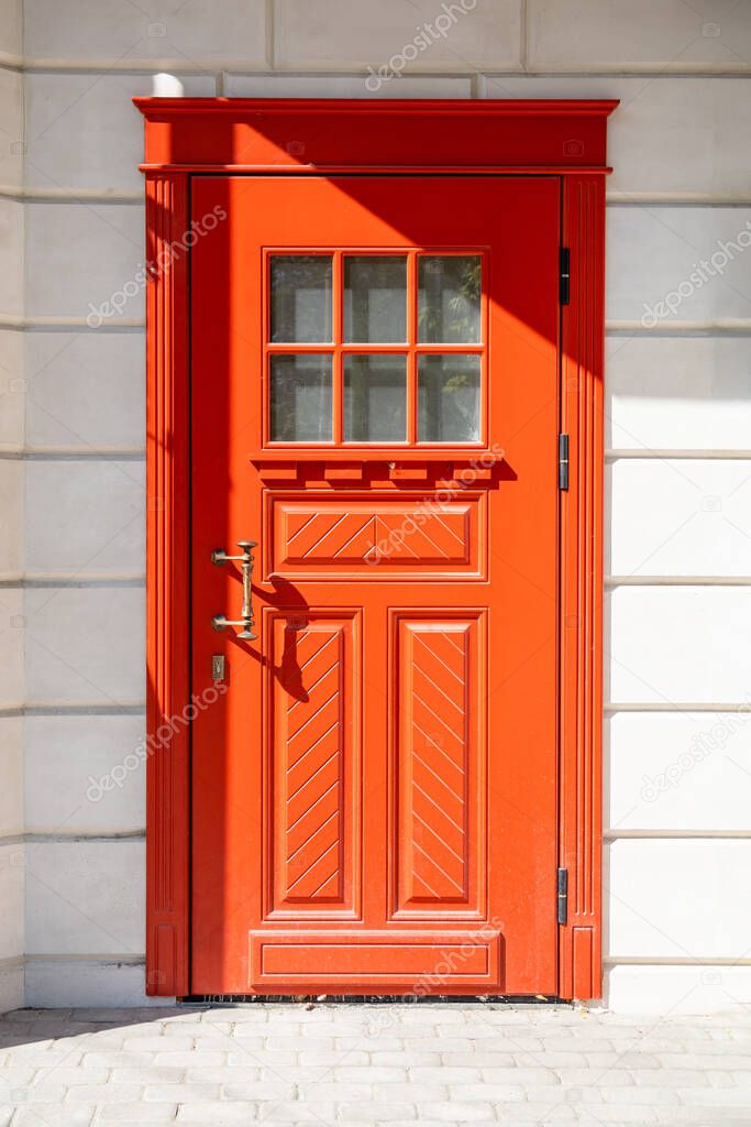 red wooden front door in a white stone wall