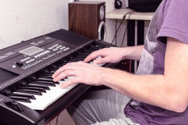 Parlak bir ev stüdyosunda sentezleyici çalan piyanistin elleri...