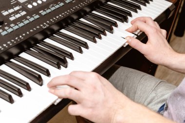 Parlak bir stüdyoda sentezleyici çalan bir piyanistin elleri.