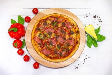 Beyaz arka planda domuz pastırmalı, dolmalık biberli ve fesleğenli pizza.