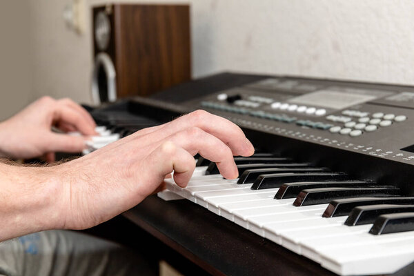 hands of a pianist man playing a synthesizer in a bright home studio