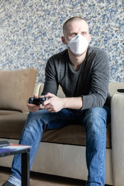 Coronavirus covid-19 salgını sırasında evinde karantinada solunum cihazı olan genç bir adam oyun konsolu oynuyor.
