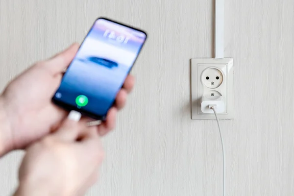 Bulanık insan eli, arka planda şarj olmak için akıllı telefonu açar.