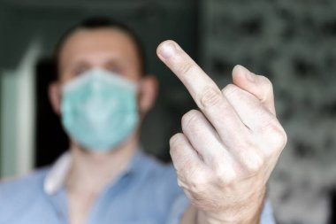 man in medical mask shows indecent gesture 