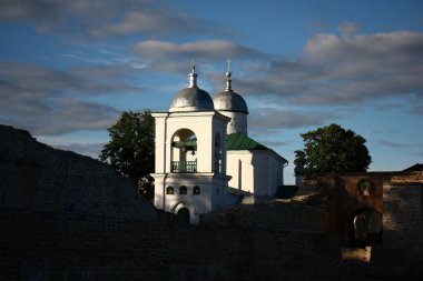 Antik Rus şehri Izborsk. Antik taş kale. Akşam güneşinin ışıkları beyaz duvarlar, bir çan kulesi ve St. Nicholas Kilisesi 'nin kubbeleri..