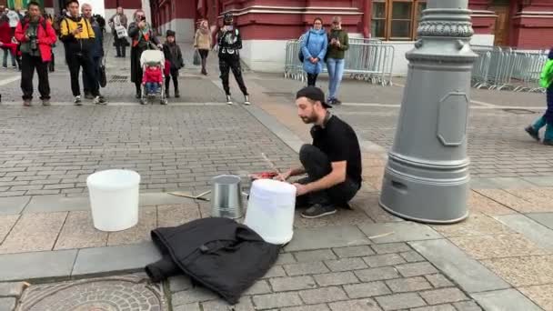 September 2019, russland moskau, Straßenmusiker, Trommler, der auf dem roten Platz auf einem hausgemachten Musikinstrument spielt, auf Eimern, auf dem Boden sitzend. — Stockvideo