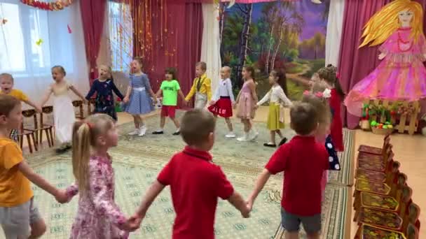 October 2019, Moscow, Russia, Kindergarten 830. Girls and boys of small age, in summer clothes, holding hands, walk in a circle and sing, in the kindergarten room. — Stock Video