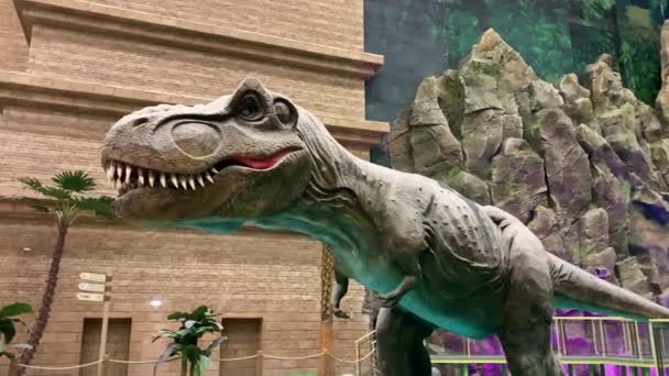 9 maart 2020, Moskou, Rusland, amusement Park Island of dreams. Dinosaurusbeeld in beweging, tegen een achtergrond van rotsen en palmbomen. — Stockvideo