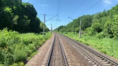 Trafikli demiryolu, doğal bir arka plan, yeşil ağaçlar, elektrik direkleriyle.
