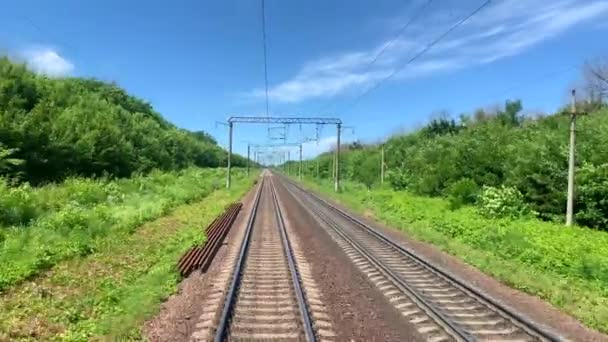 Ferrocarril con tráfico, con un fondo natural, árboles verdes, postes eléctricos . — Vídeos de Stock