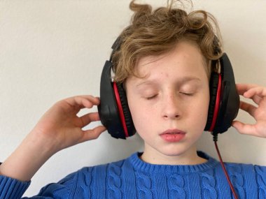 Mavi ceketli genç bir adam kafasında büyük kulaklıklarla müzik dinliyor..