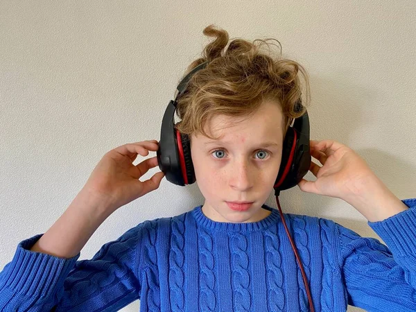 Un jeune homme vêtu d'une veste bleue écoute de la musique, avec de gros écouteurs sur la tête . — Photo