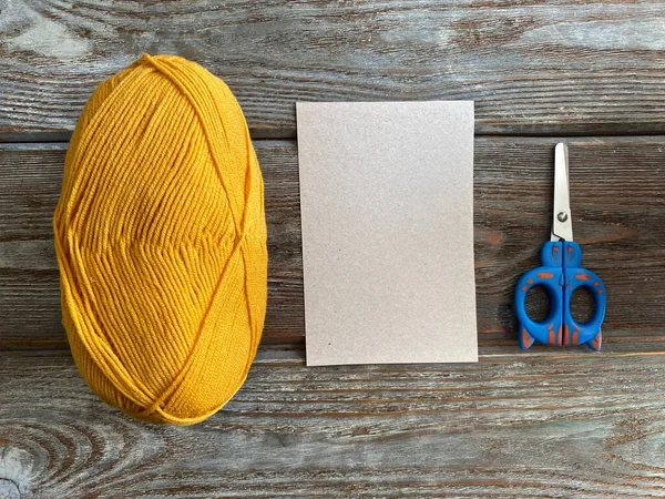 Yellow yarn and cardboard with scissors are ready for needlework. visual aid how to make a monster out of yarn. — Stock Photo, Image