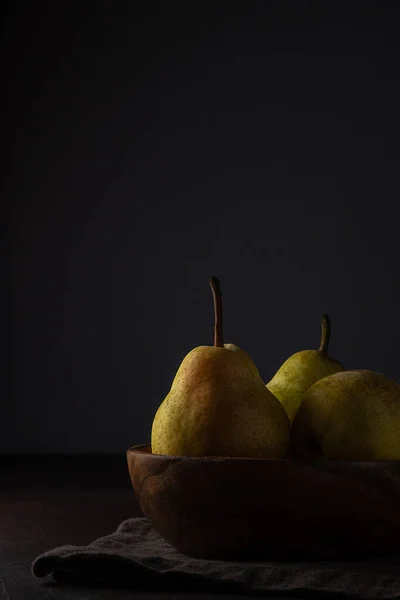 Three ripe juicy pears on a dark background with copy space