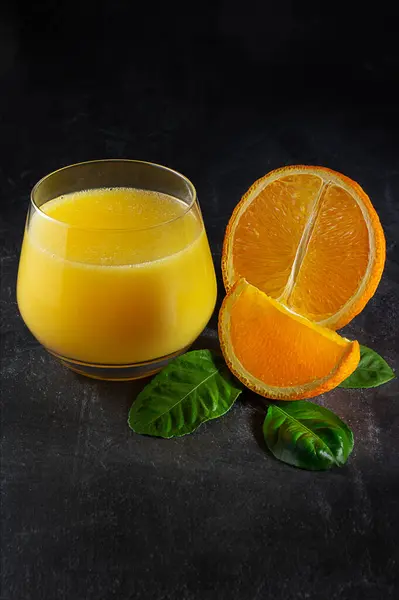 Glas Met Vers Sinaasappelsap Sinaasappels Groene Bladeren Een Donkere Achtergrond — Stockfoto