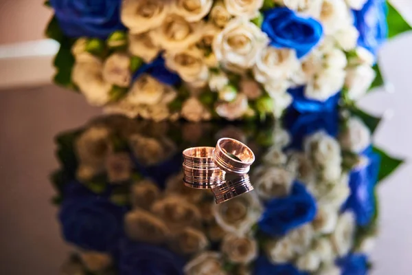 wedding rings on the table with bridal bouquet