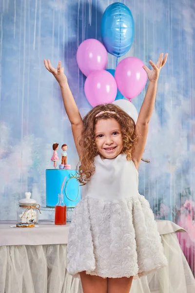 Children's funny birthday party in decorated room with balloons. Happy little girl celebrate International Children's Day. Funny child play at home