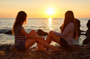 Gün doğumunda sahilde iki kadın. Kardeşler doğanın tadını çıkarır ve şafakla birlikte buluşurlar.