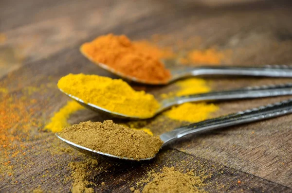 Bir kara tahta günü süslü gümüş kaşık içinde renkli köri baharatlar 