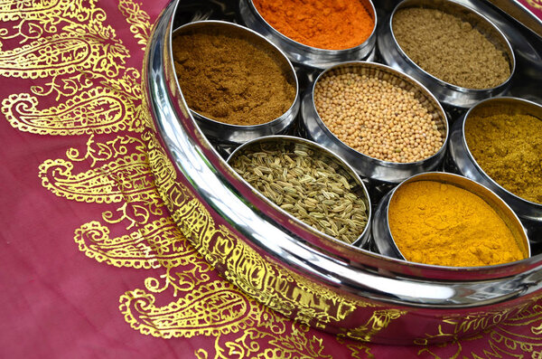 Indian Cuisine Cookery Spices in Silver Pots on a Pink and Gold 