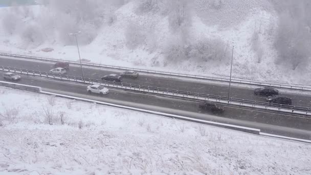 Cars driving on snowy road in winter, traffic on highway in snowfall, blizzard — Stock Video