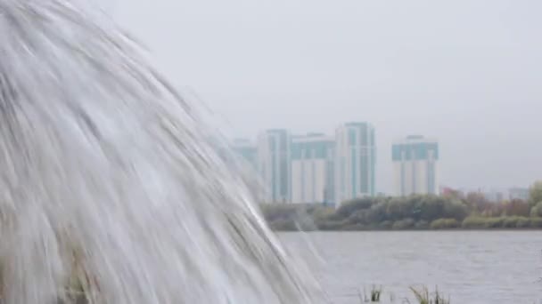 A tiszta, átlátszó víz áramlása a város hátterében, toronyházak. Vízesés, patak — Stock videók