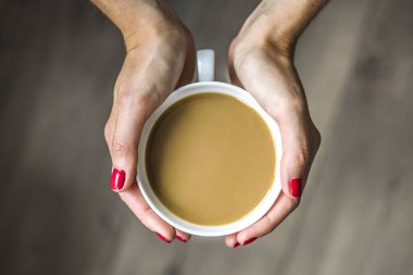 Kadın eli bir fincan kahve tutuyor.