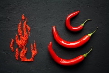 Kırmızı kırmızı biber ve kırmızı biber yakın mesafeden siyah bir yüzeye alev yaprakları şeklinde dağılmış.