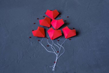 Origami kırmızı kalpleri, havada uçuşan balon şeklinde koyu mavi bir zemin üzerinde kağıttan yapılmıştır. Sevgililer Günü. Tasarım için boş alan.
