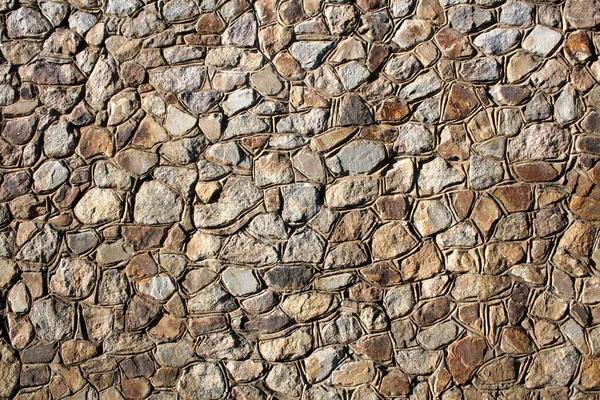 在阳光灿烂的日子里 一堵由不同大小的天然石头筑成的墙 — 图库照片