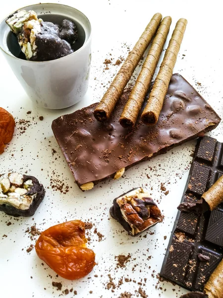さまざまな種類のチョコレート 白いテーブルの上のチョコレートチューブは ココアパウダー コーヒー豆 乾燥アプリコットを振りかけた ストックフォト