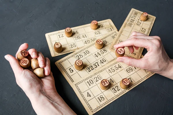 A Lotto game, a woman puts barrels on cards with numbers.
