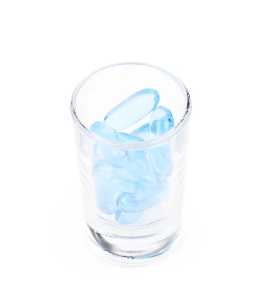 Shot glas vol softgel pillen geïsoleerd — Stockfoto