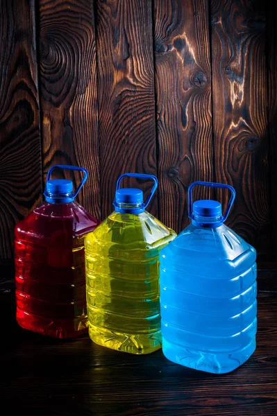 Big plastic colored bottles on a dark wood background