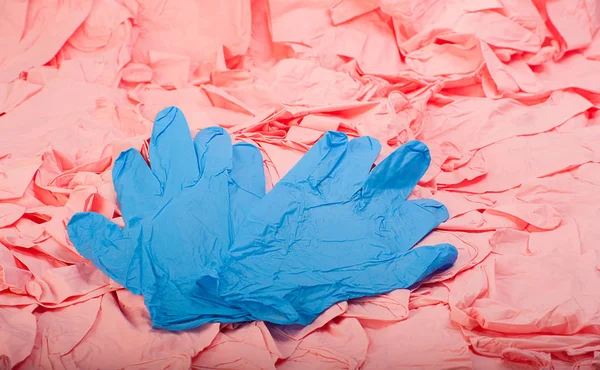 Nova luva médica de látex azul no fundo de um monte de luvas de borracha rosa — Fotografia de Stock